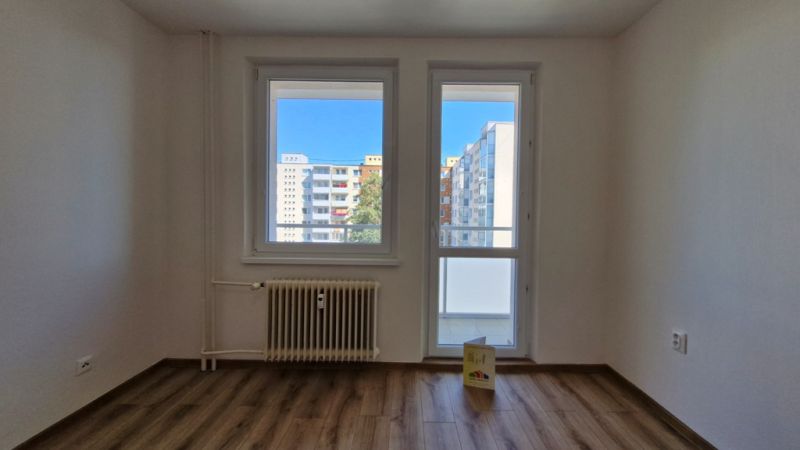 A room in a 3-room apartment with a wooden decor floor and a glass view of the surroundings.