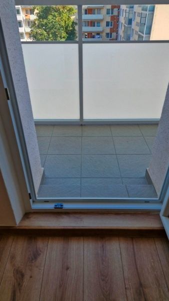 View from a 3-room apartment to a balcony with glass and a wooden decor floor.