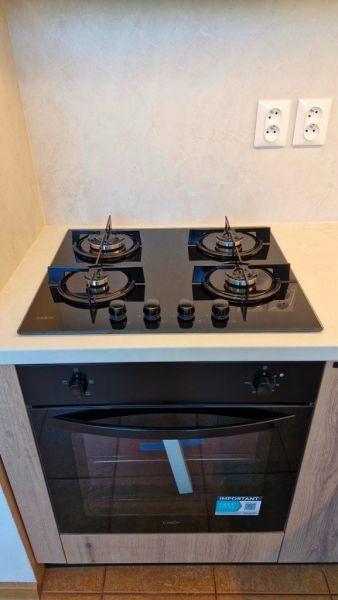 Kitchen with a gas stove and oven, 3-room apartment, floor with wooden decor.