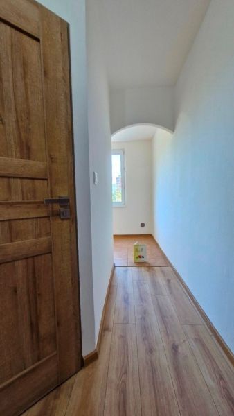 A narrow hallway with wooden doors and a floor with a wooden decor in a 3-room apartment.