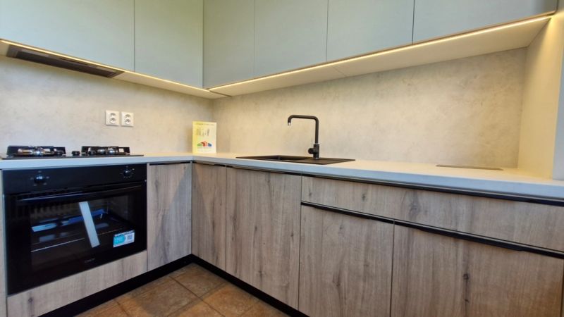 A kitchen in a 3-room apartment with a wooden decor floor and modern equipment.