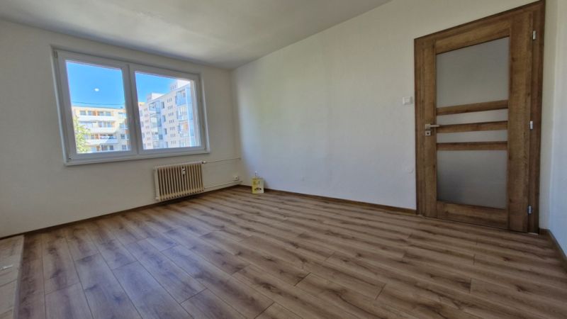 A room in a 3-room apartment with a wooden decor floor and white walls.