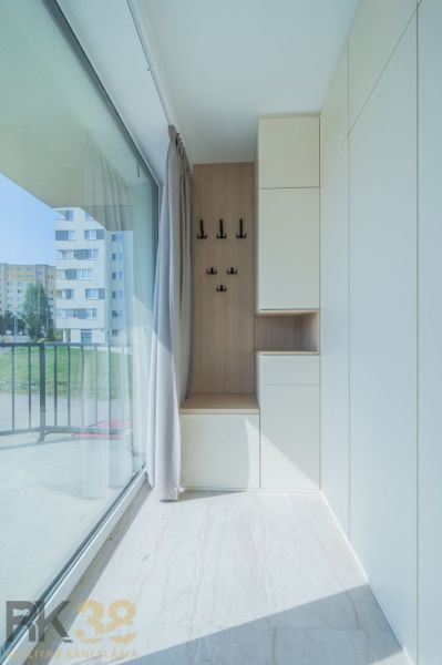 A bright hallway with a glass wall, hooks, and storage space in a 4-room apartment.
