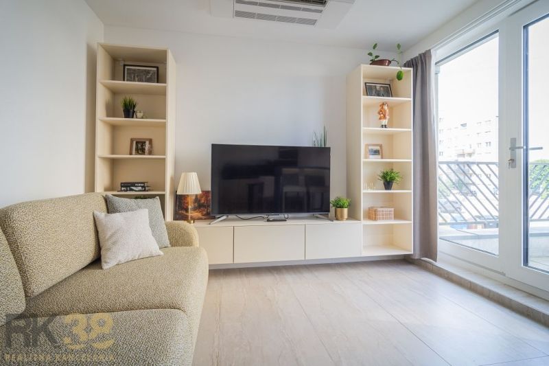 Living room with a television, sofa, and shelves in a 4-room apartment, floor with wooden decor.