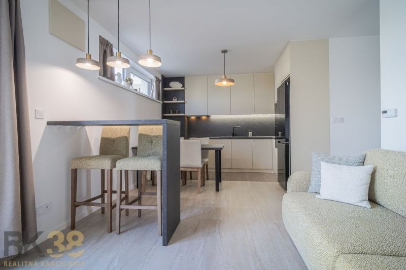 A kitchen in a 4-room apartment with bar stools, a stove, and a floor with a wood decor.