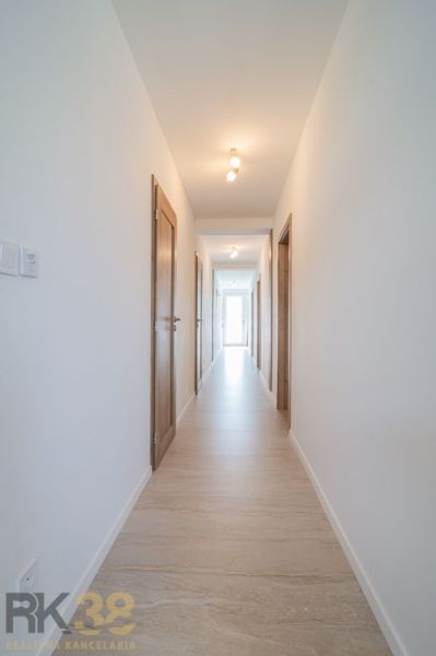 A bright hallway with a light wooden-patterned floor in a 4-room apartment.