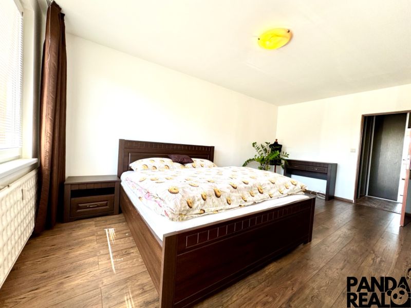 A bedroom with wooden furniture and a wooden decor floor in a studio apartment.