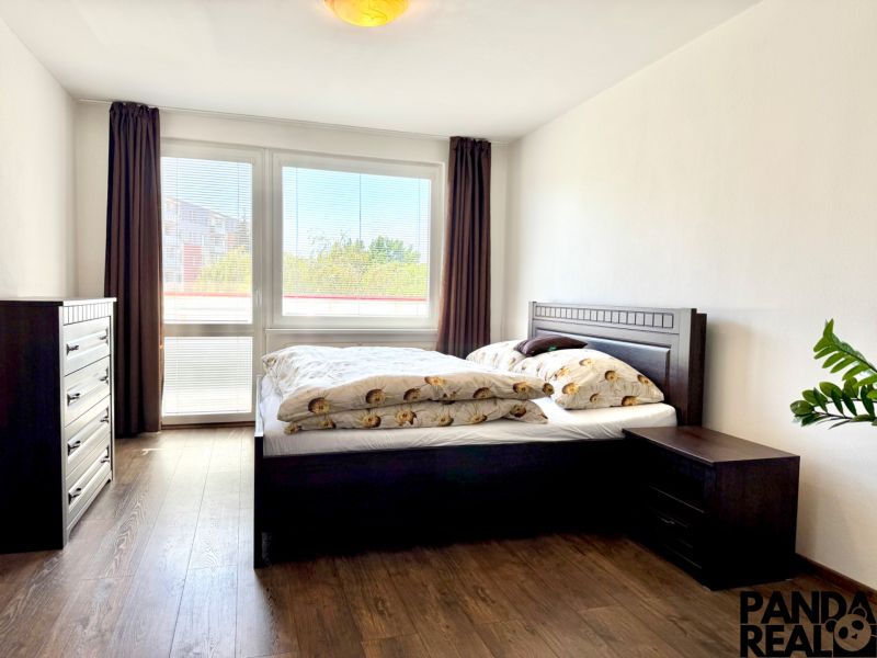 Bedroom with a bed and a dresser, wooden decor flooring, in a studio apartment.