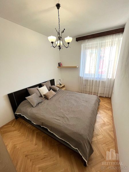 Bedroom with a bed and chandeliers, floors with wood decor in a 3-room apartment.