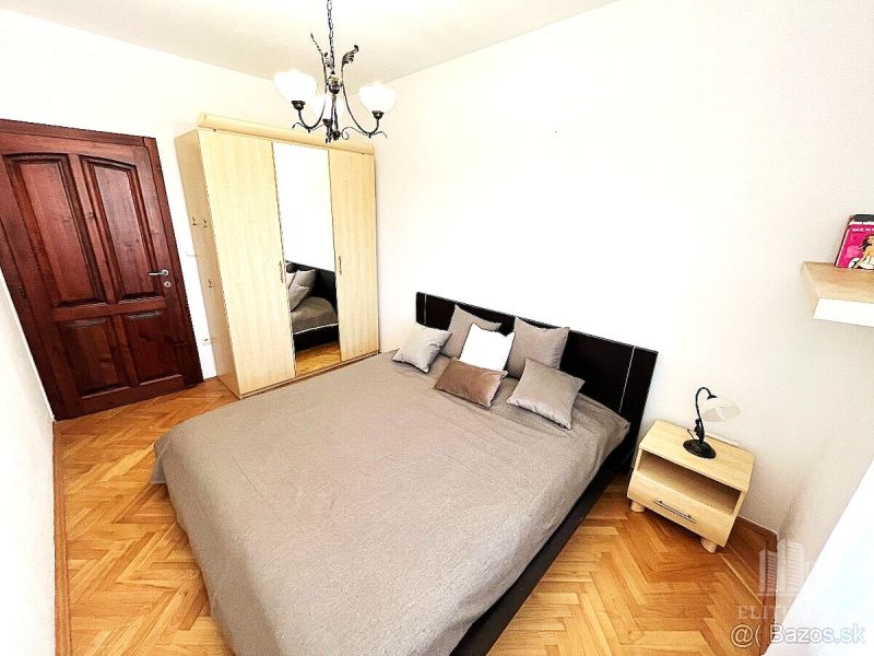 A bedroom in a 3-room apartment with a bed, a wardrobe, and a floor with a wooden decor.