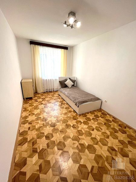 A room with a bed, a wooden decor floor, minimalist furniture in a 3-room apartment.