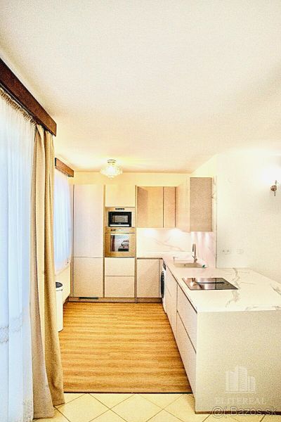 A kitchen in a 3-room apartment with white cabinets and a wooden decor floor.