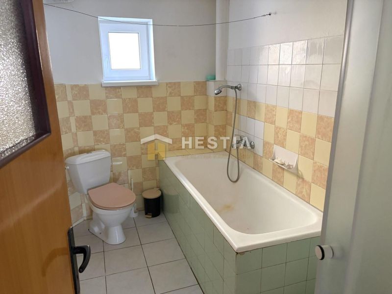 Bathroom with a bathtub and toilet in a family house, with tiled decoration.