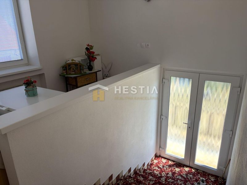 Interior of a family house with a colorful carpet, staircase, and decorative items.