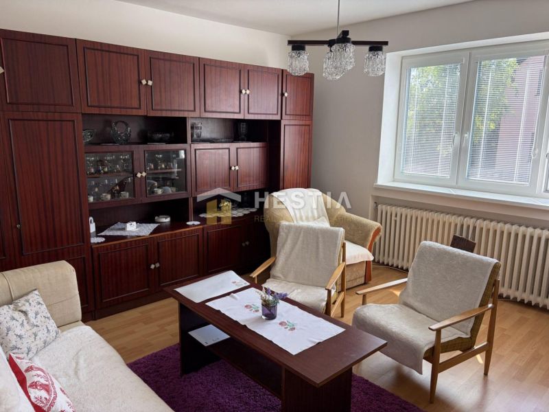 Living room with wood-patterned flooring, wooden living room furniture, and a large window in a family house.