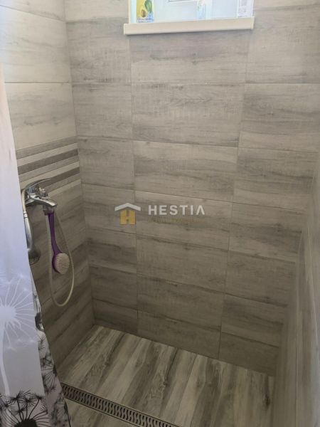 Shower corner in a family house with wood-patterned tiles and a curtain.