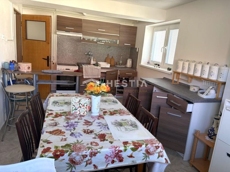 A kitchen in a family house with a floral tablecloth and a kitchen unit with a wooden decor.