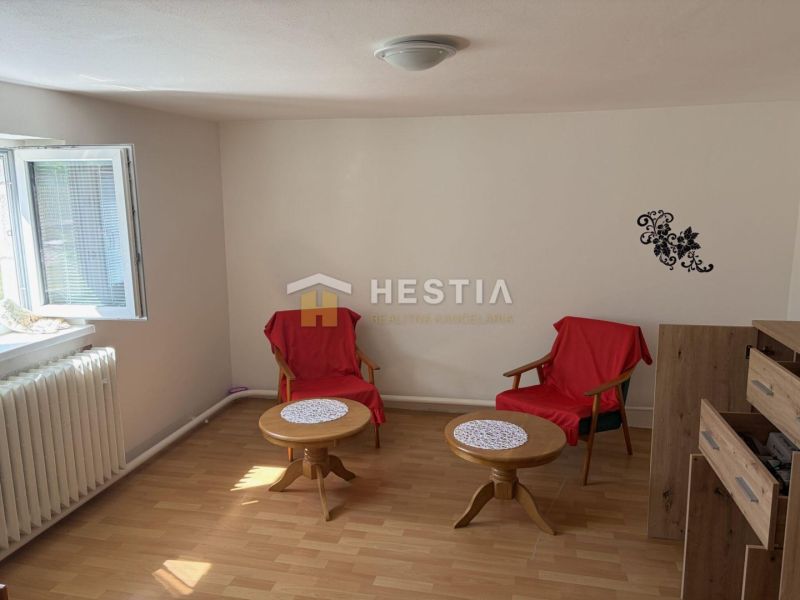 Interior of a family house with two chairs, tables, and a wooden-patterned floor.