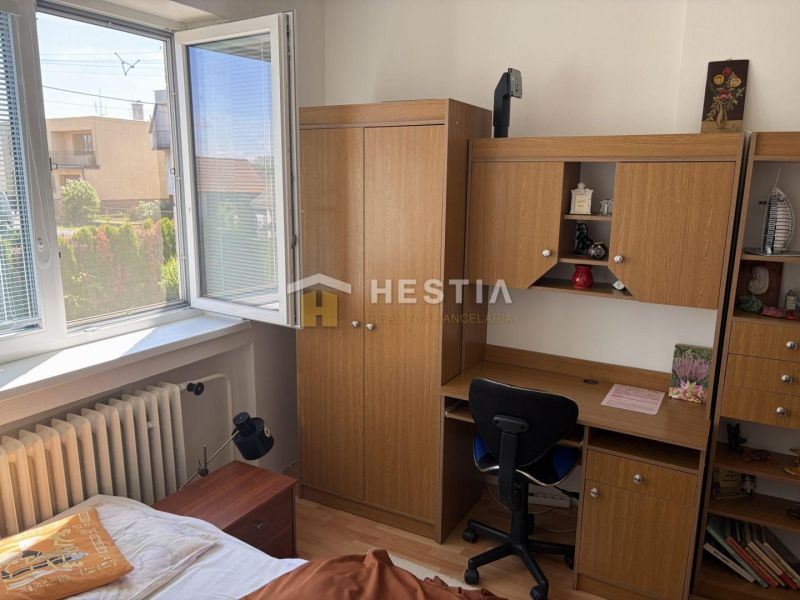 A room in a family house with a desk, a wardrobe, and a view from the window.