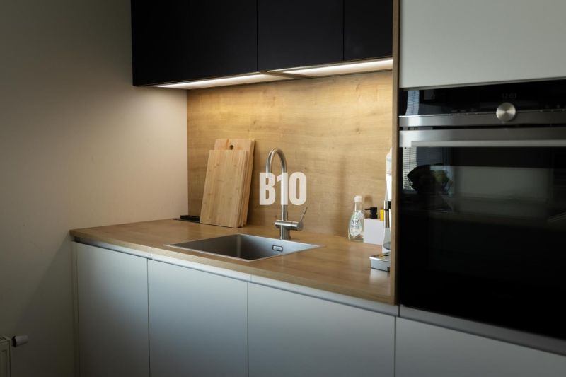 A kitchen with wooden decor, a sink, black cabinets, appliances, and wooden countertops in a 3-room apartment.