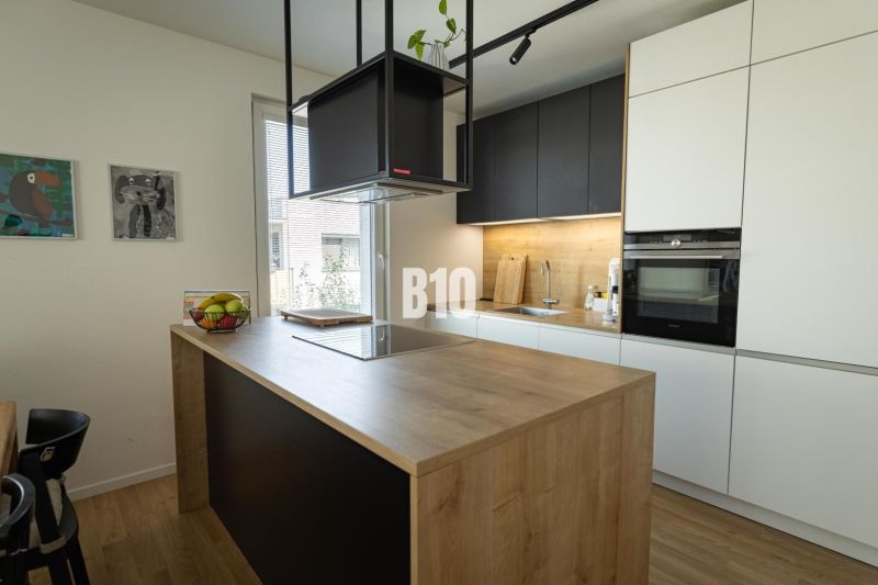 A kitchen in a 3-room apartment with an island and a wooden decor floor.