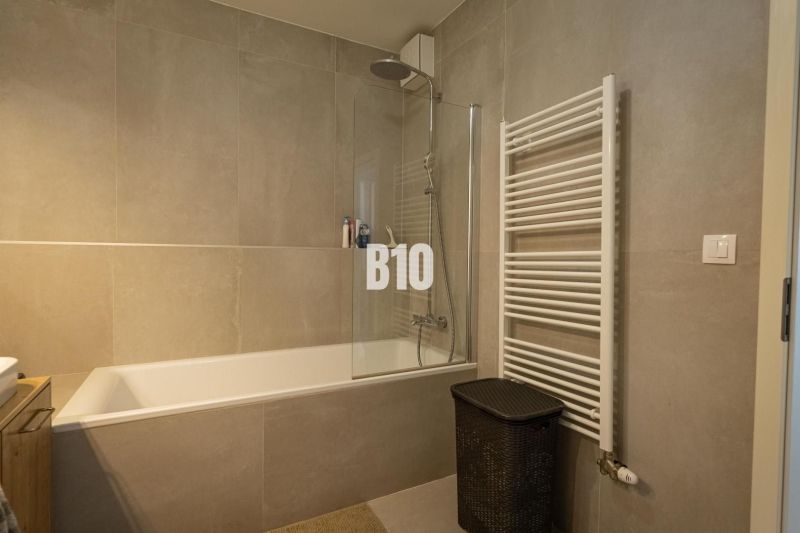 Bathroom in a 3-room apartment with a bathtub, shower, and ladder radiator.