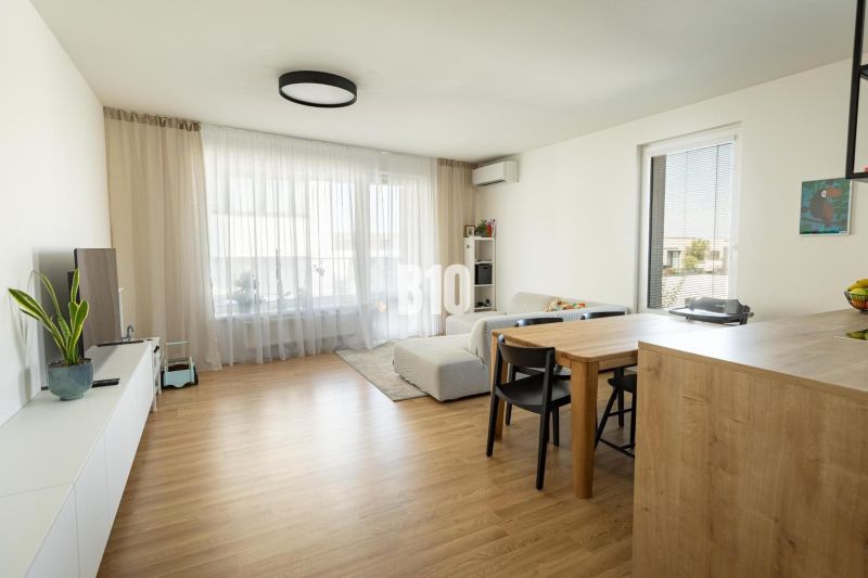 Living room in a 3-room apartment with a wooden decor floor and light curtains.