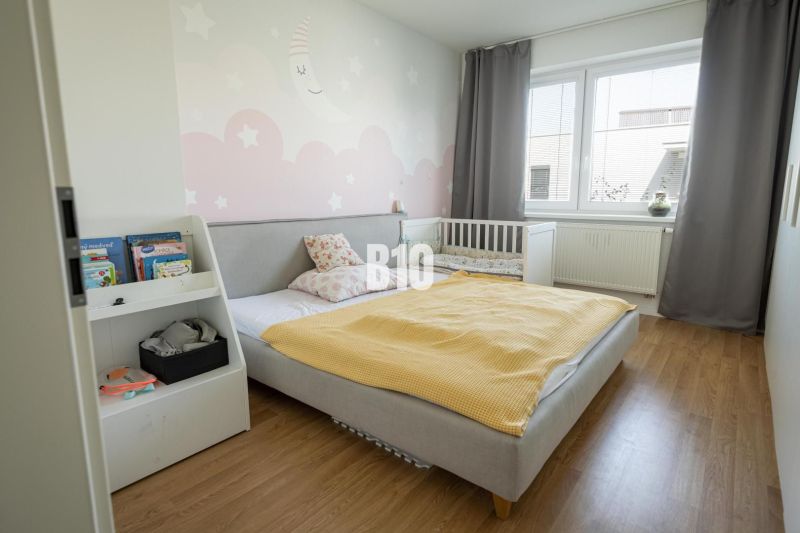 Children's room with a bed, crib, wooden decor flooring, and a bookshelf in a 3-room apartment.