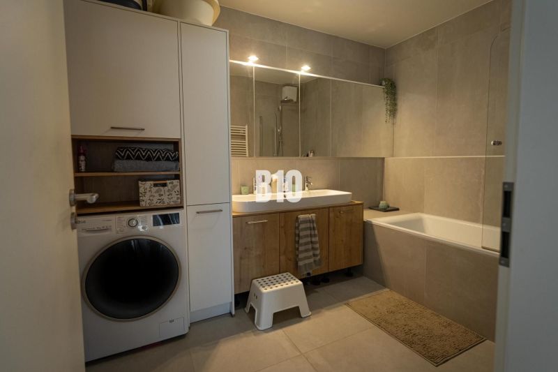 A bathroom in a 3-room apartment with a bathtub, cabinets, and a washing machine.