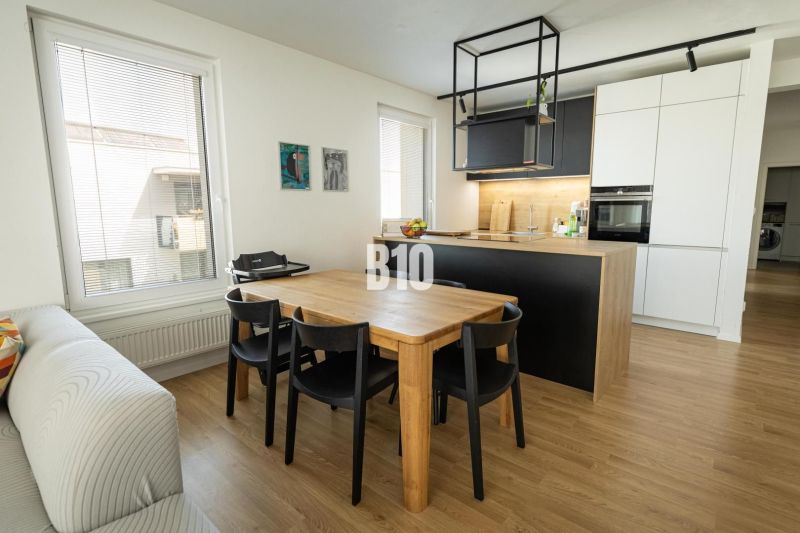 Dining room with a wooden table and a kitchen island in a 3-room apartment.
