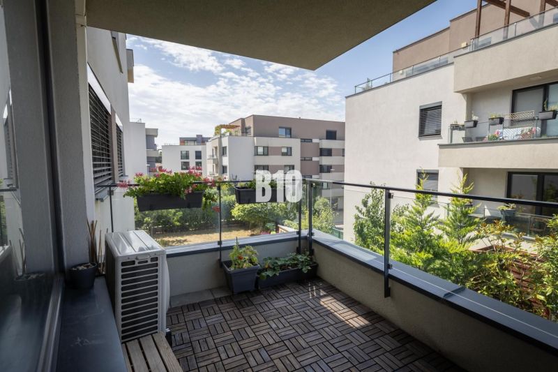A balcony with a wooden decor floor and flowers in a 3-room apartment in Bratislava IV.