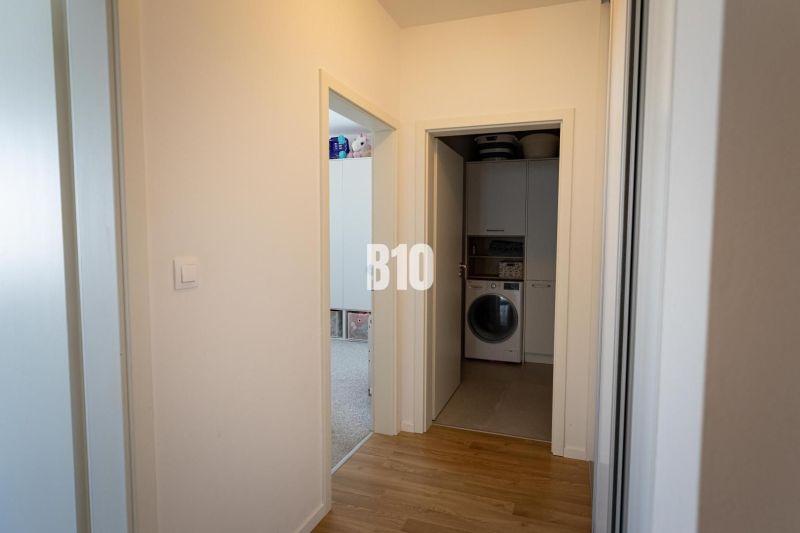Hallway with a washing machine, wooden decor flooring, room doors, 3-room apartment.