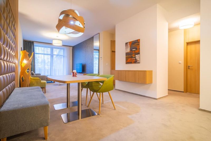 Bright living room with a dining table and carpeted floor in a holiday apartment.