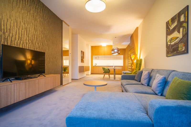 A recreational apartment with a wood-patterned floor, a comfortable sofa, and a television.