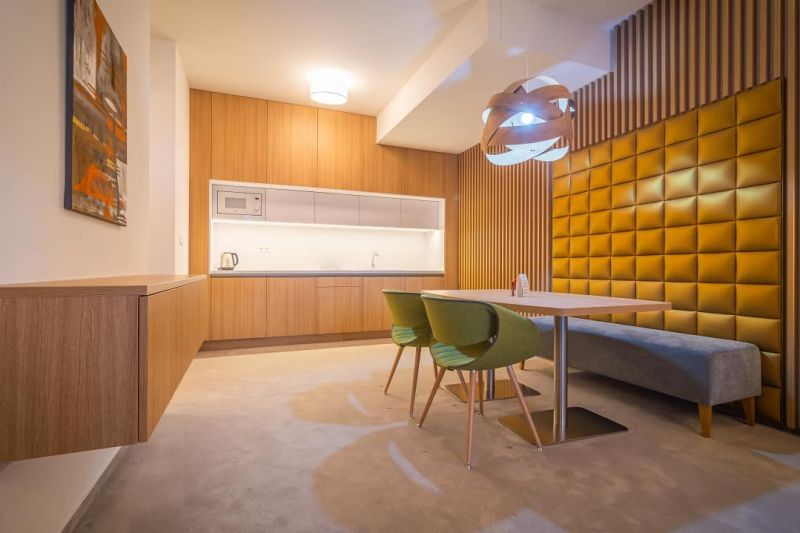 Kitchen in a holiday apartment with wooden cabinets, table, and green chairs.