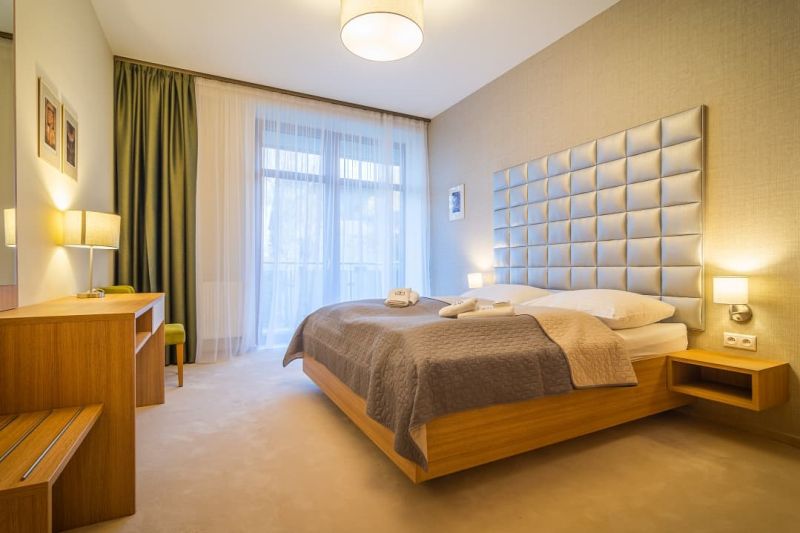A bedroom in a holiday apartment with a large headboard and a wooden decor floor.