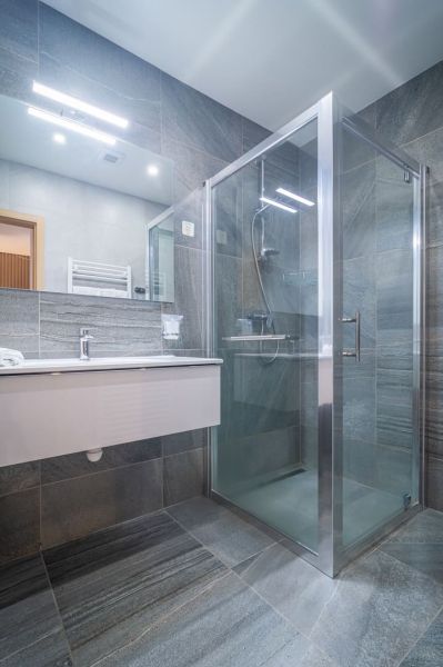 A bathroom in a vacation apartment with a spacious shower and a large mirror.