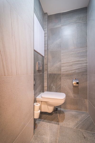 Bathroom with ceramic tiles and a wall-mounted toilet in a Holiday Apartment.