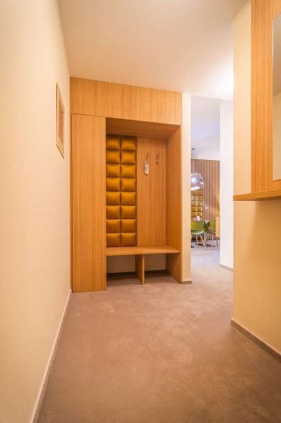 Interior of a holiday apartment with a coat rack wall and softly lit hallway.