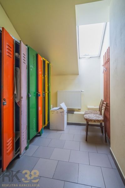 Colorful cabinets, wooden chairs, radiator, and slanted window in the dining area.