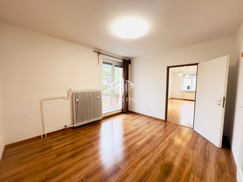 A room in a 2-room apartment with large windows and a floor with a wooden decor.