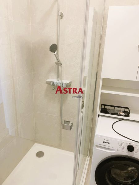 A bathroom in a 3-room apartment with a shower and a washing machine.