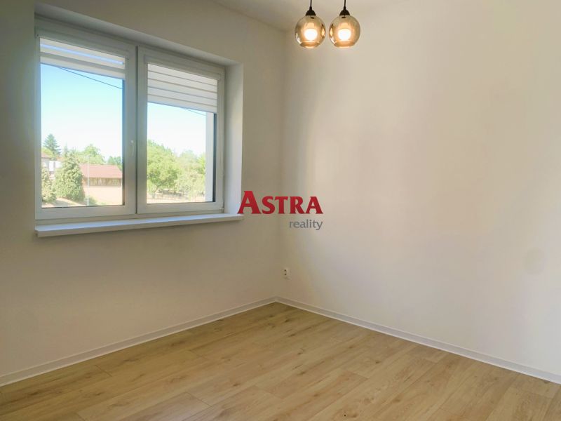 A room with a wooden decor floor in a 3-room apartment, light walls, window.