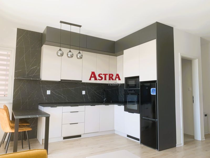 A kitchen in a 3-room apartment with modern black and white cabinets.