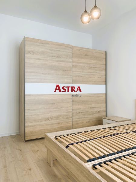 In the bedroom of a three-room apartment with a wooden decor floor, there is a wardrobe.