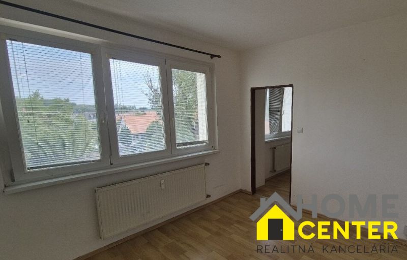 A room with white walls, large windows, and a floor with a wooden design.
