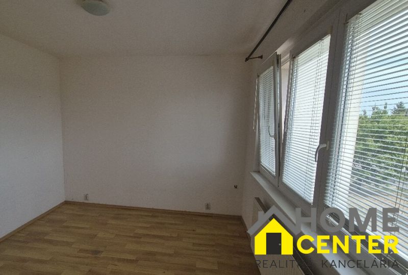 A room in a one-room apartment with a wooden decor floor and large windows.