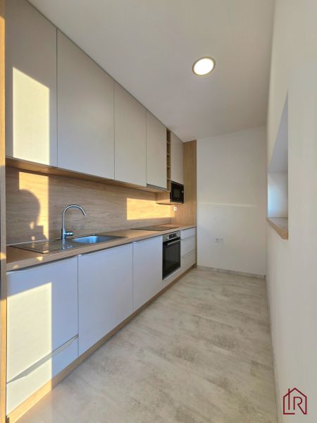 Kitchen in a 2-room apartment, white kitchen unit, floor with wood decor.