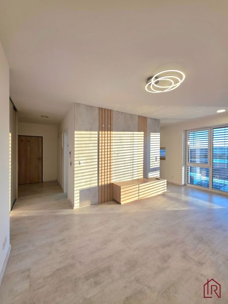 A bright living room with wood-patterned flooring and modern lighting in a two-room apartment.