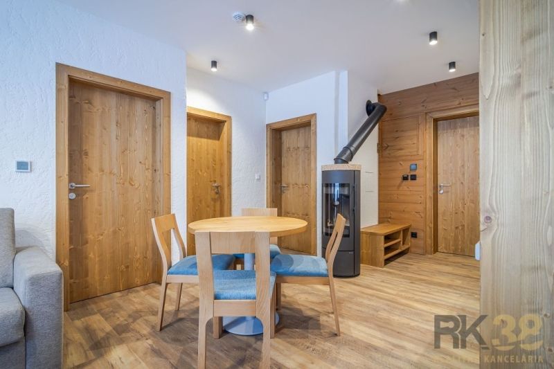 Recreational apartment with wood-patterned flooring, a round table, and a wood-burning stove.